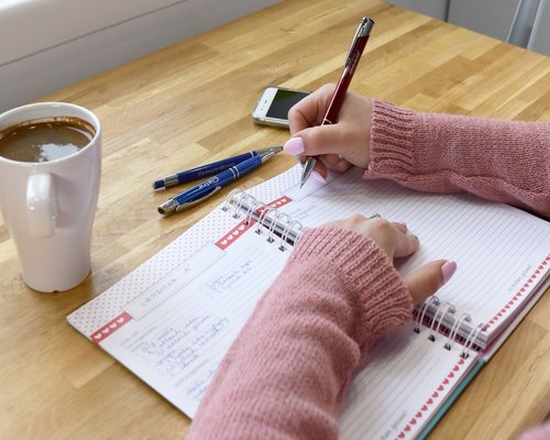 Woman organizing her daily planner on a wooden desk